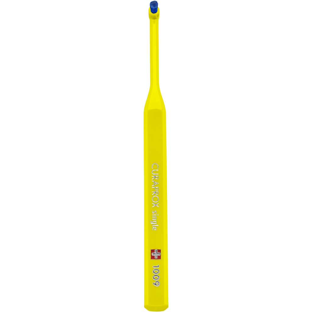 A yellow CURAPROX single 1009 toothbrush, part of the brand's trusted products range, features a small round brush head and a flat, wide handle, shown upright against a plain white background.