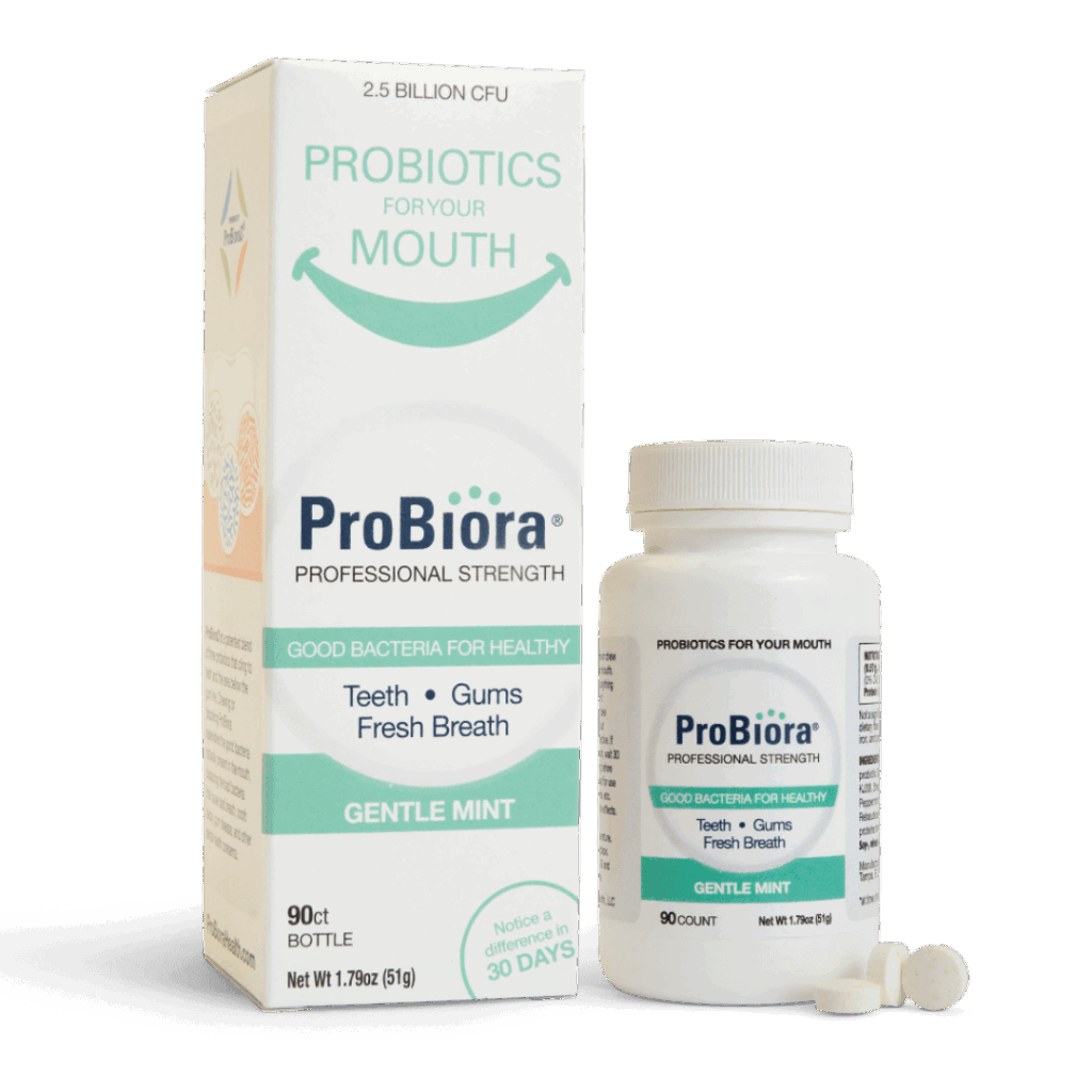 A white bottle and box of ProBiora Professional Strength oral probiotic products, labeled for promoting healthy teeth, gums, and fresh breath in a gentle mint flavor. Two white tablets are placed in front of the bottle.